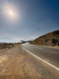 A scenic road winding through diverse Indian landscapes under a clear sky.