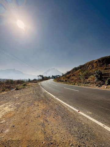 A scenic road winding through diverse Indian landscapes under a clear sky.