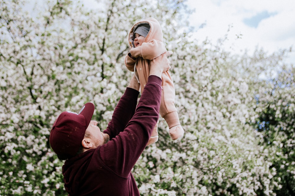 a man holding a baby up in the air