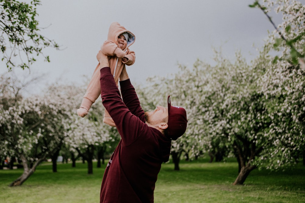 a man holding a baby up in the air