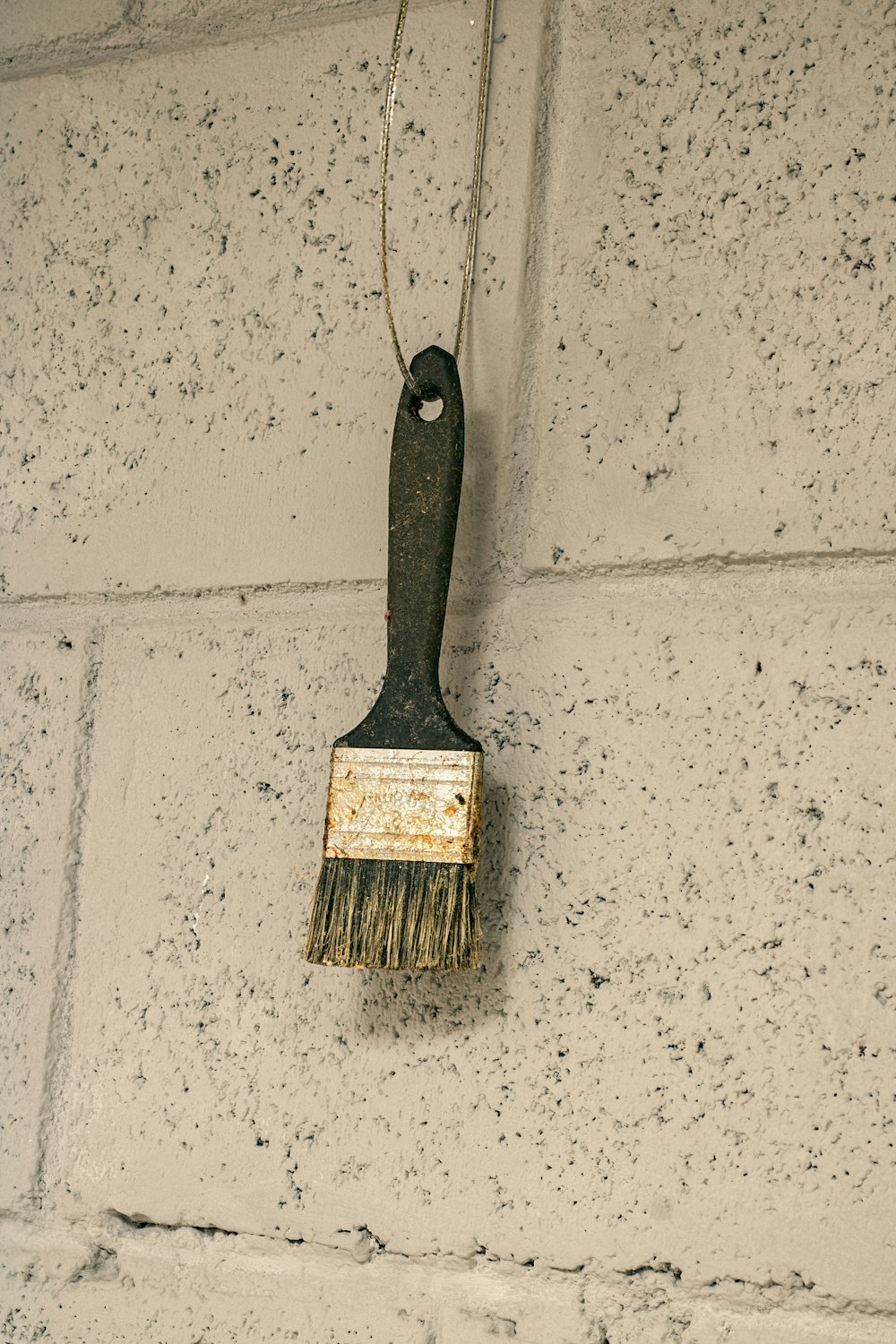 a paint brush hanging on a brick wall