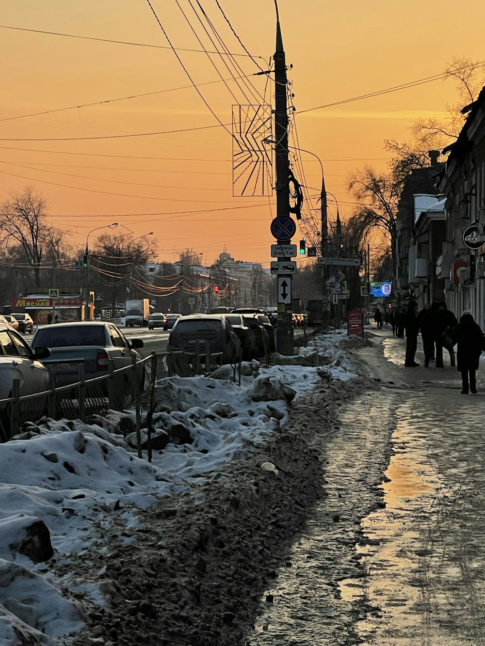 a couple of people walking down a snow covered street