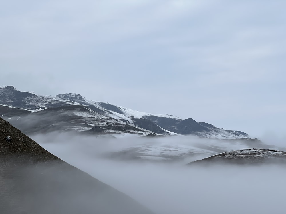 uma montanha coberta de nevoeiro e nuvens com um pássaro empoleirado no topo dela