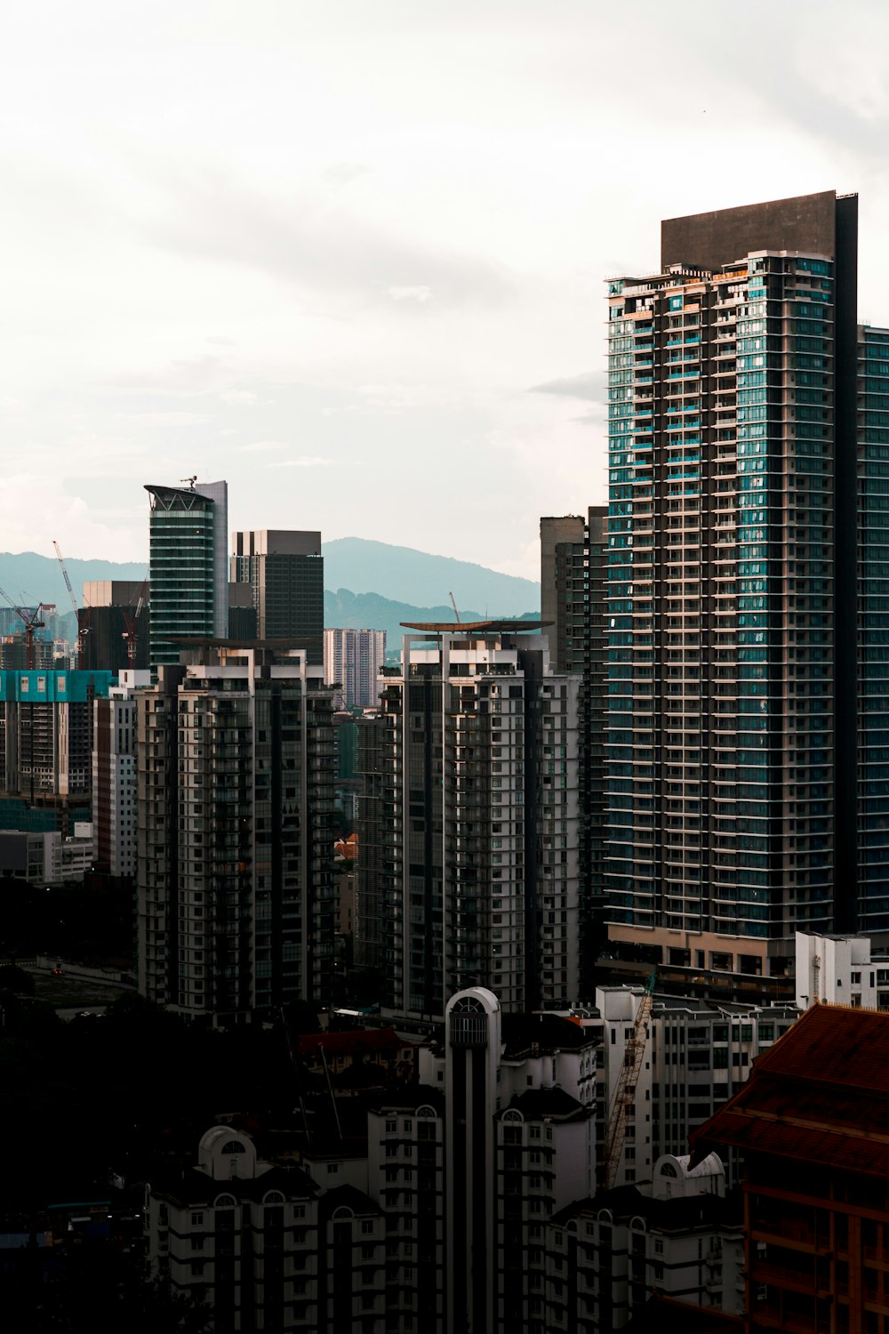a city skyline with tall buildings and mountains in the background