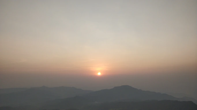 A serene sunset casting warm light over a rugged mesa landscape.
