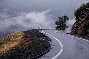 Wide-angle view of a misty morning bike ride along a winding mountain road