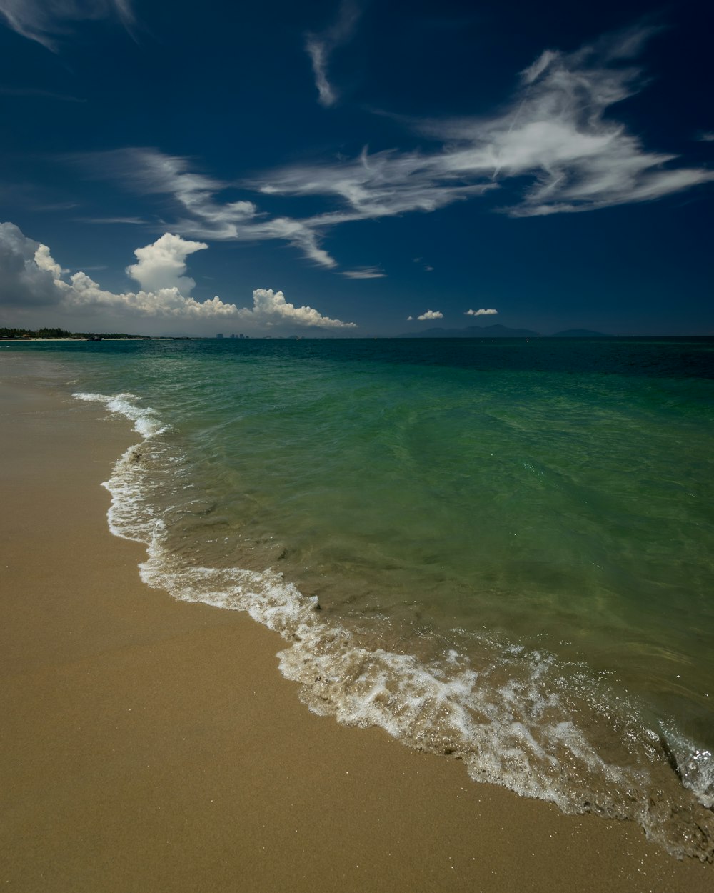 a sandy beach with waves coming in to shore