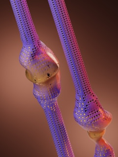 Two stylized, perforated bone structures are set against a warm brown gradient background. The bones display a gradient effect of blue and purple hues with scattered golden yellow dots, creating a visually striking pattern.