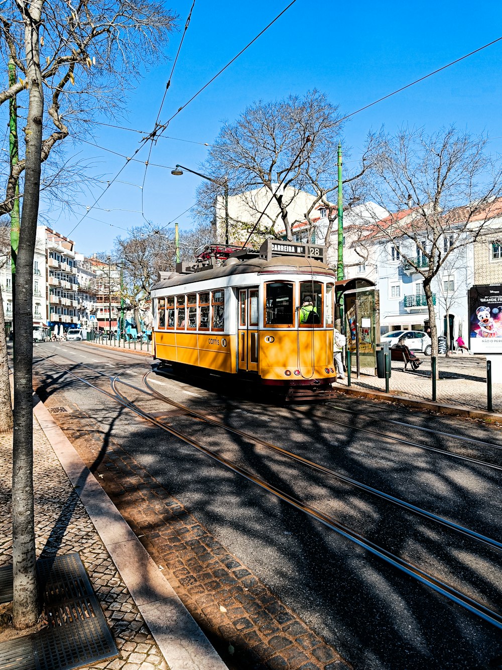 a yellow trolley car traveling down a street next to tall buildings