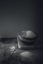 A close-up of fine white kitchen salt crystals in a rustic wooden bowl.