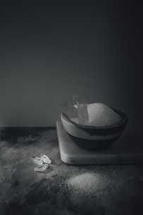 A close-up of fine white kitchen salt crystals in a rustic wooden bowl.
