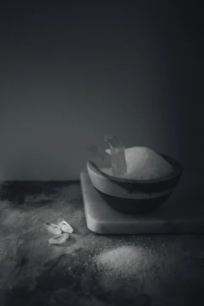 Minimalist composition featuring a small pile of premium salt crystals on rustic wood, highlighting texture.