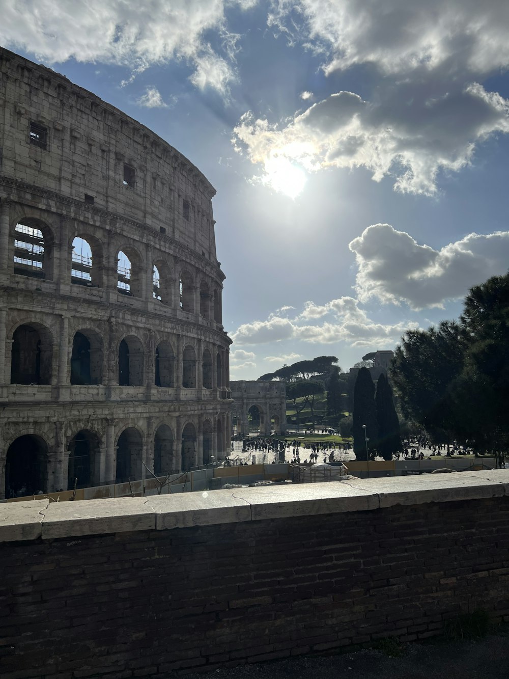 the sun shines through the clouds over the roman colossion