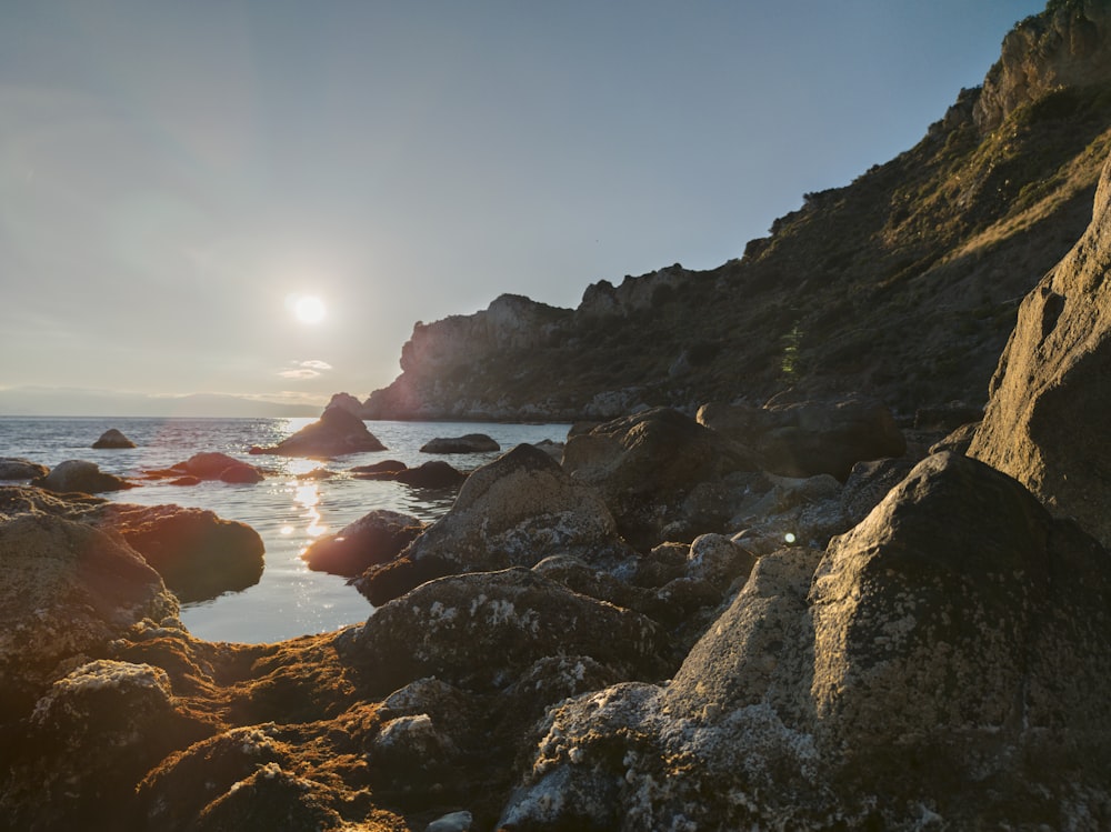 El sol se está poniendo sobre una playa rocosa