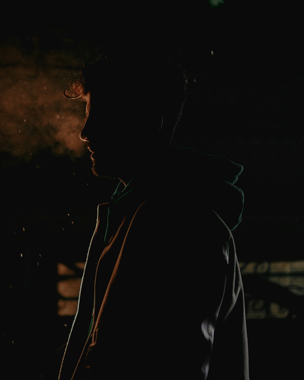 a man standing in the dark with a cigarette in his mouth