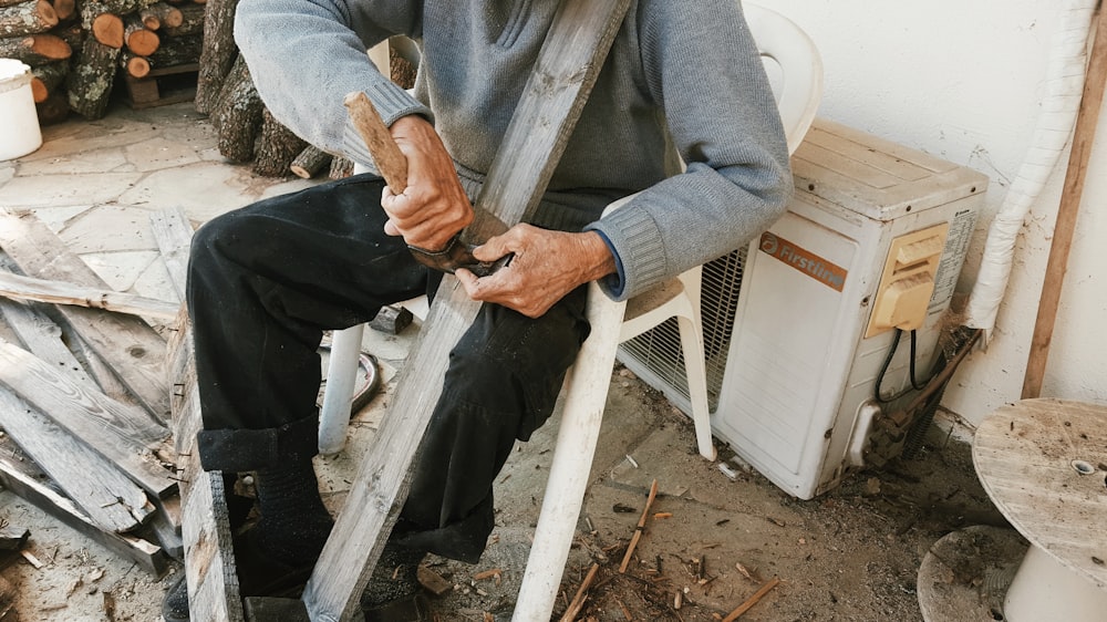 a man sitting on a chair holding a piece of wood