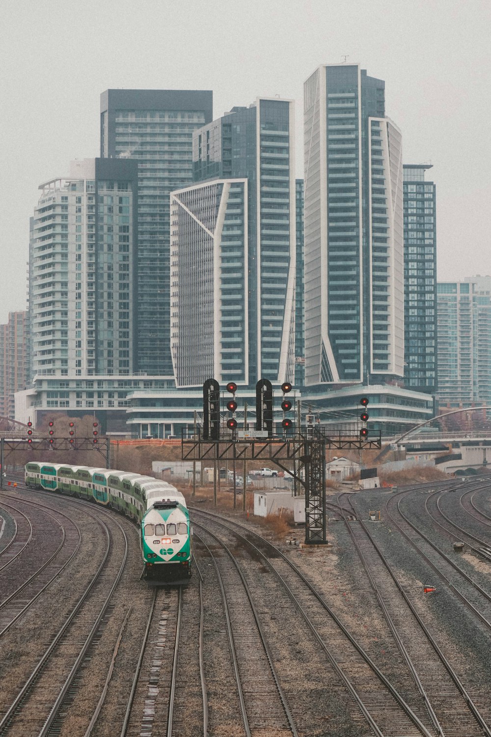 Un treno verde e bianco che viaggia oltre edifici alti