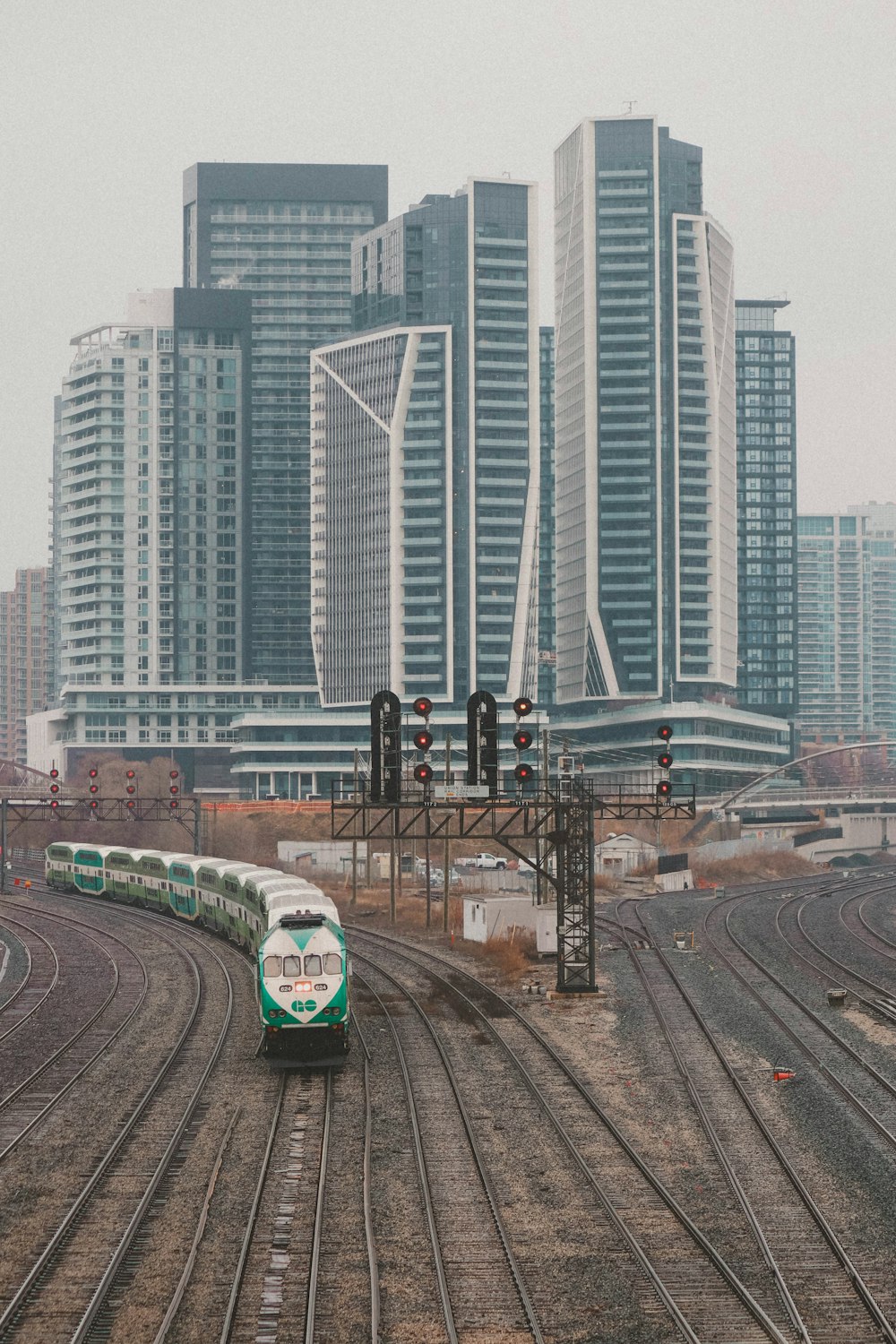 a green and white train traveling past tall buildings