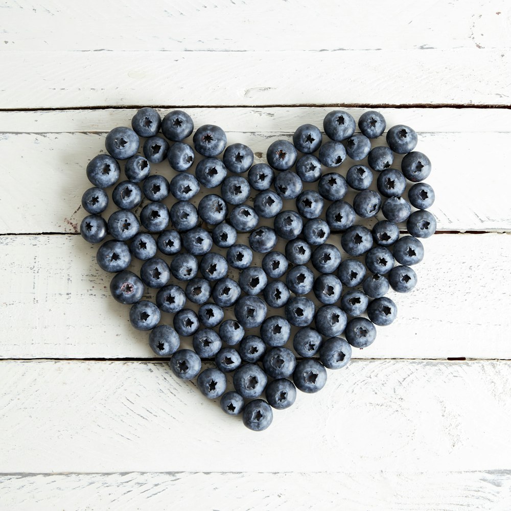 a heart made out of blueberries on a white wooden surface