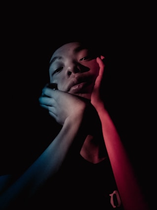 A warm, cinematic portrait of a focused young adult studying with deep blue and cream tones in the background.