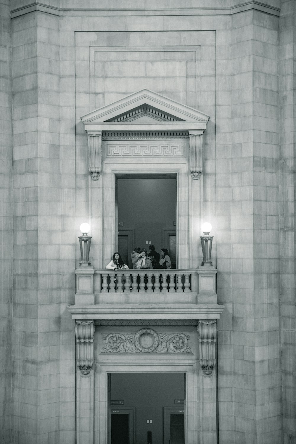 a black and white photo of people sitting on the balcony of a building