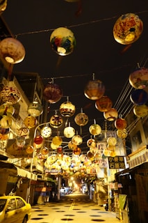 Close-up of colorful lanterns hanging above a lively street during a festive evening tour.