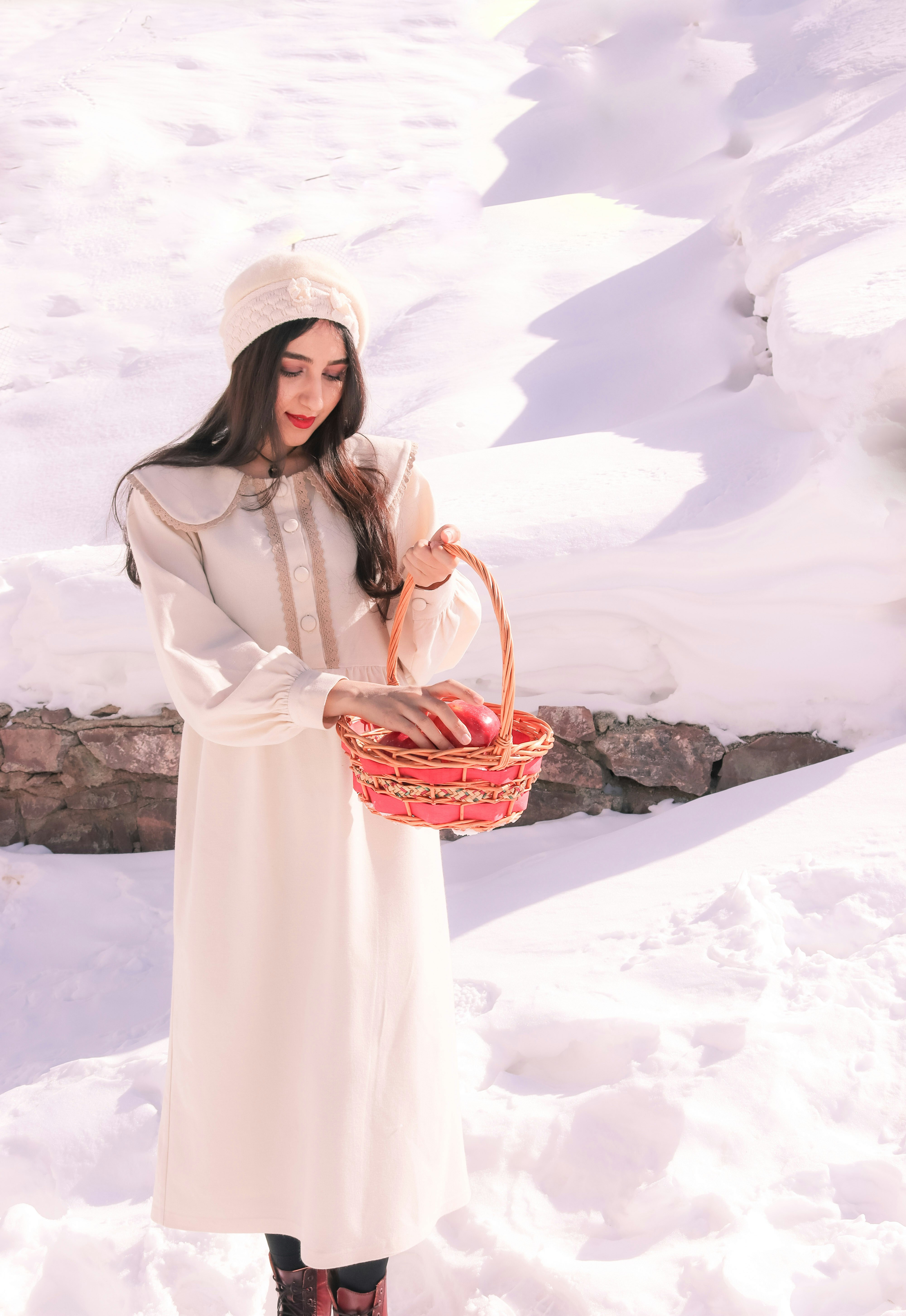 a woman standing in the snow holding a basket