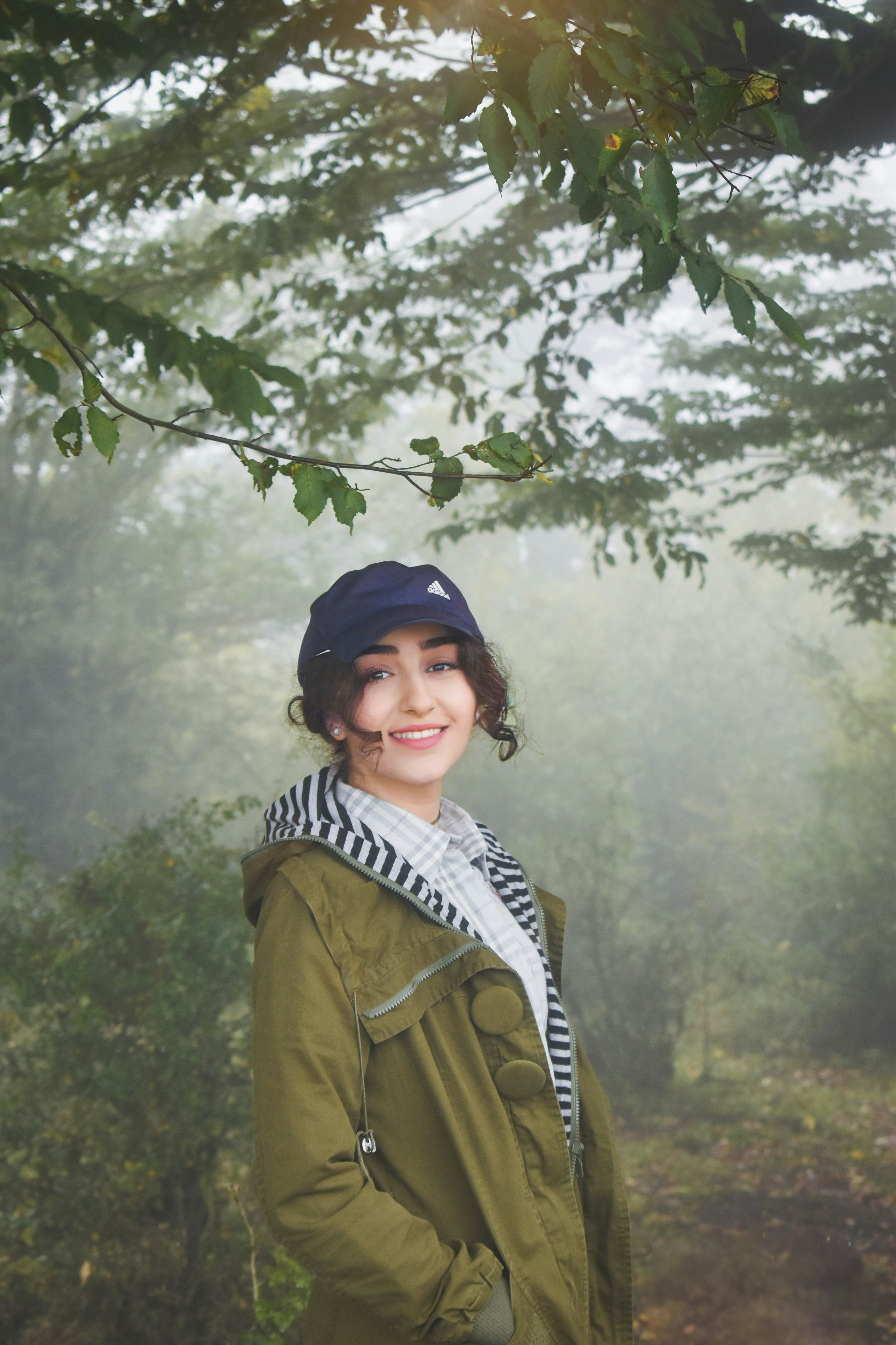 a woman standing under a tree in the woods
