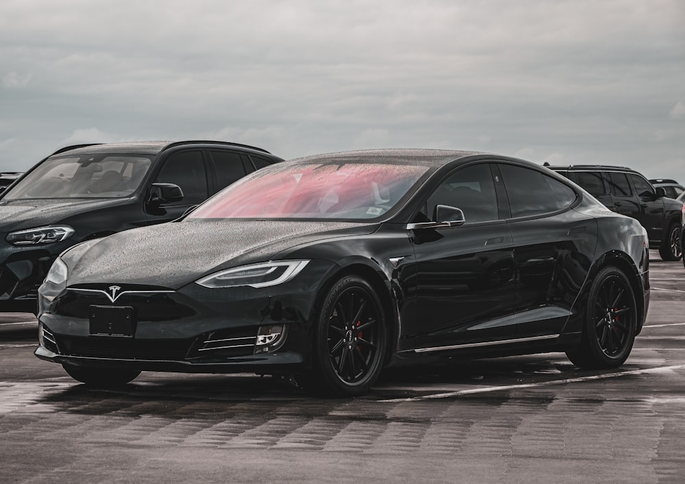 a black tesla parked in a parking lot