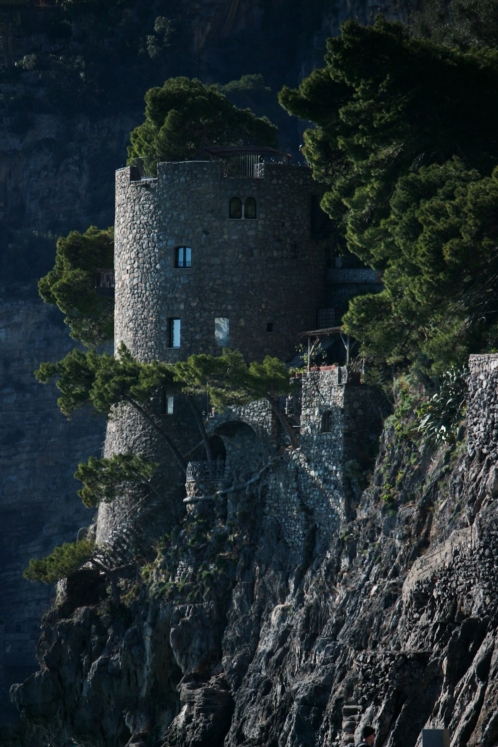 a stone tower on a rocky cliff with trees growing out of it
