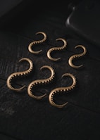 Set of sturdy metal hooks arranged on a wooden plank showcasing their finish.