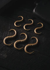 A set of matching bathroom hooks with antique brass finish arranged neatly on a wooden panel.