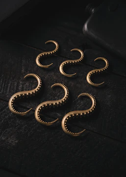 A set of matching bathroom hooks with antique brass finish arranged neatly on a wooden panel.
