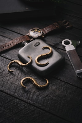 A classic silver flask placed next to a vintage pocket watch on a rustic wooden surface.