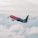 A commercial airplane with 'More to Love' written on the fuselage ascends through a cloudy sky, showcasing a gradient color scheme from red to purple.