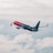 A commercial airplane with 'More to Love' written on the fuselage ascends through a cloudy sky, showcasing a gradient color scheme from red to purple.