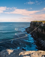 a man walking across a rope over the ocean
