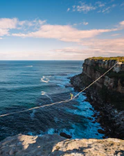 a man walking across a rope over the ocean