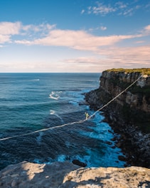 a man walking across a rope over the ocean