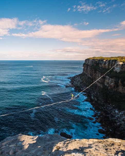 a man walking across a rope over the ocean