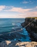 a man walking across a rope over the ocean