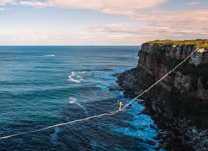 a man walking across a rope over the ocean
