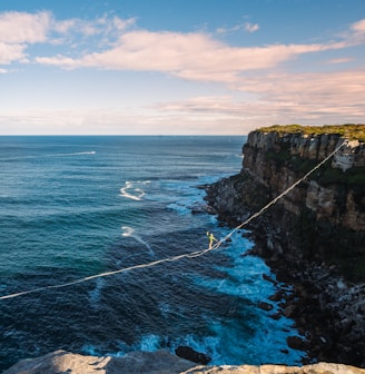 a man walking across a rope over the ocean