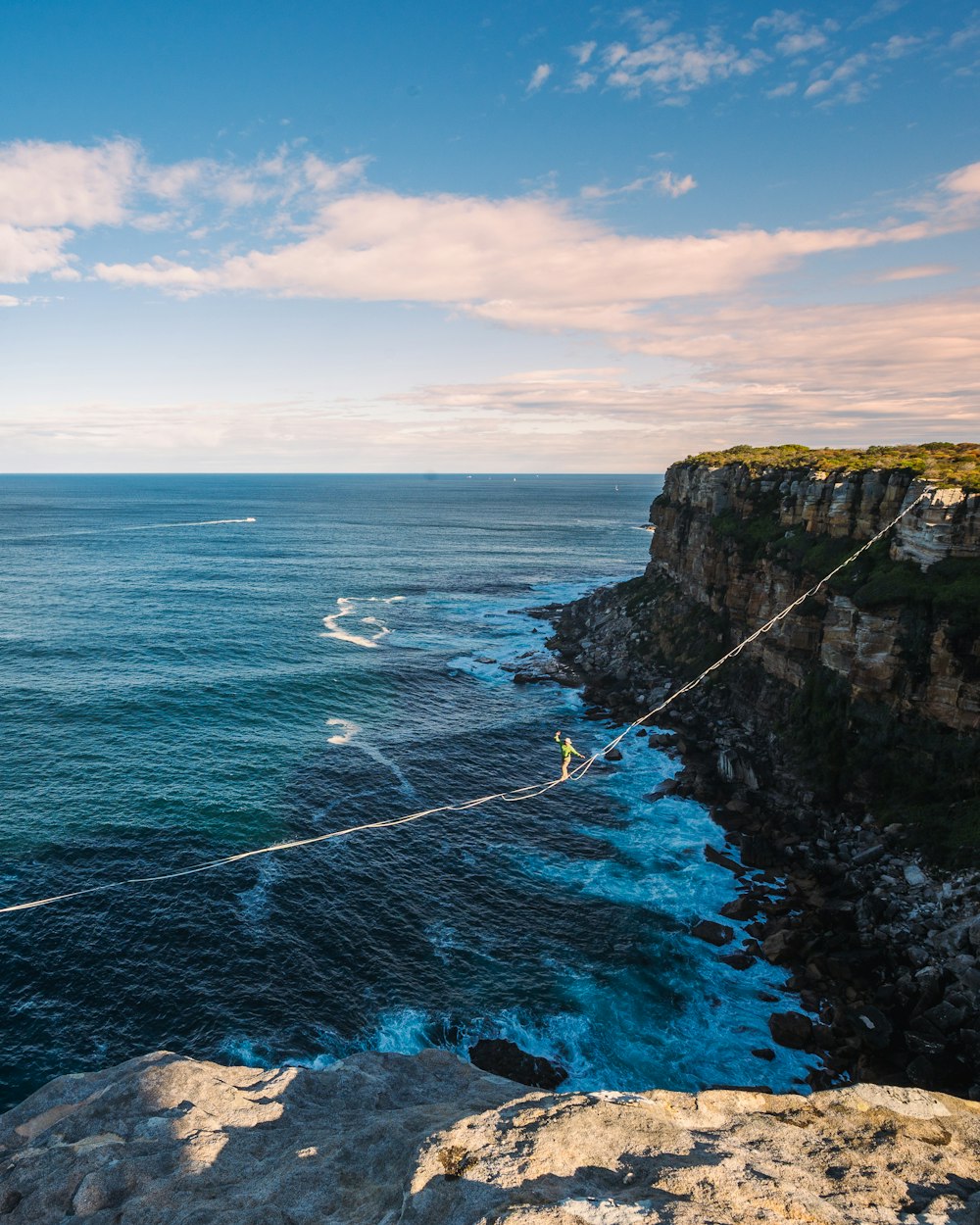 a man walking across a rope over the ocean