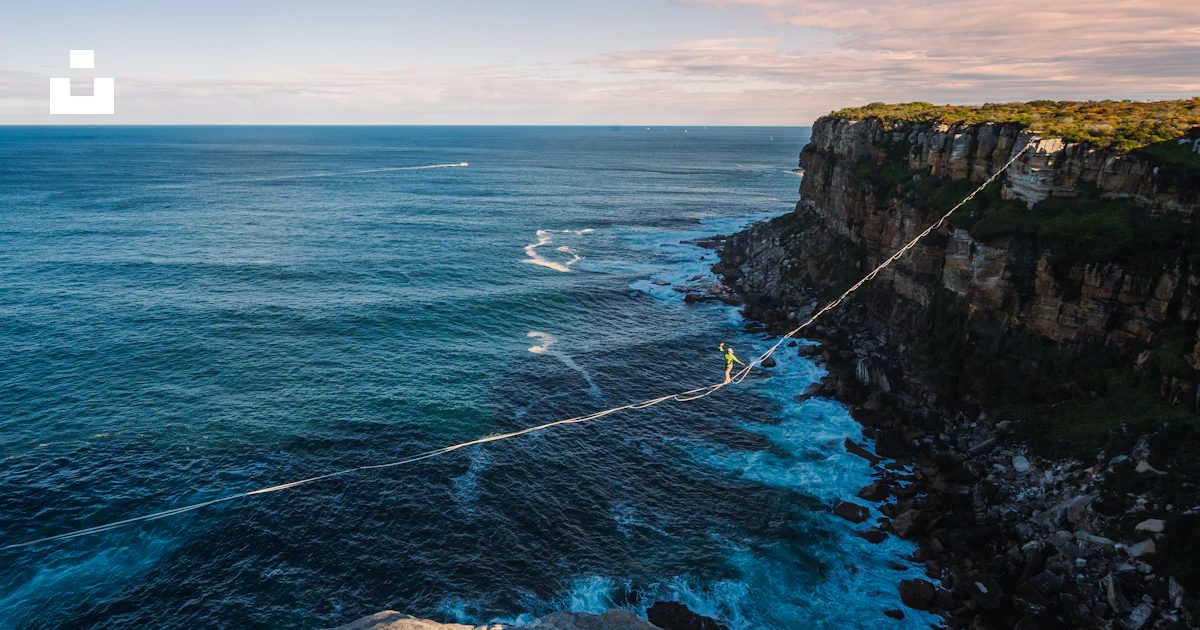 A rope is attached to the edge of a cliff near the ocean photo – Free ...