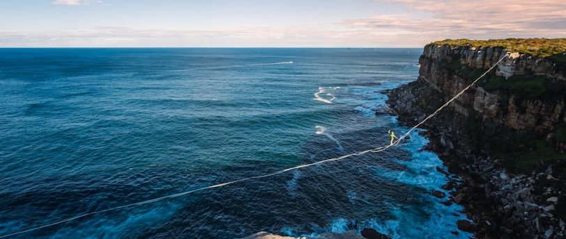 a rope is attached to the edge of a cliff near the ocean