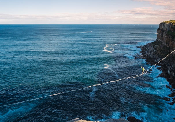 a rope is attached to the edge of a cliff near the ocean