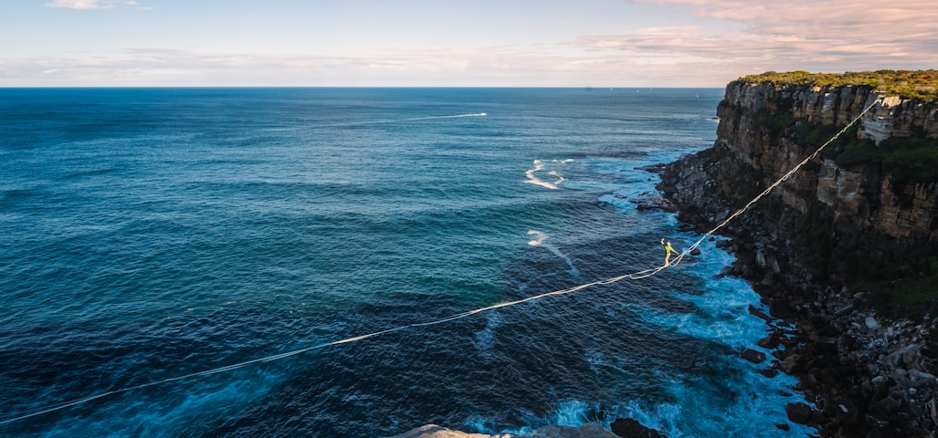 a rope is attached to the edge of a cliff near the ocean