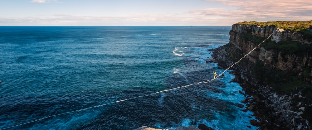 a rope is attached to the edge of a cliff near the ocean