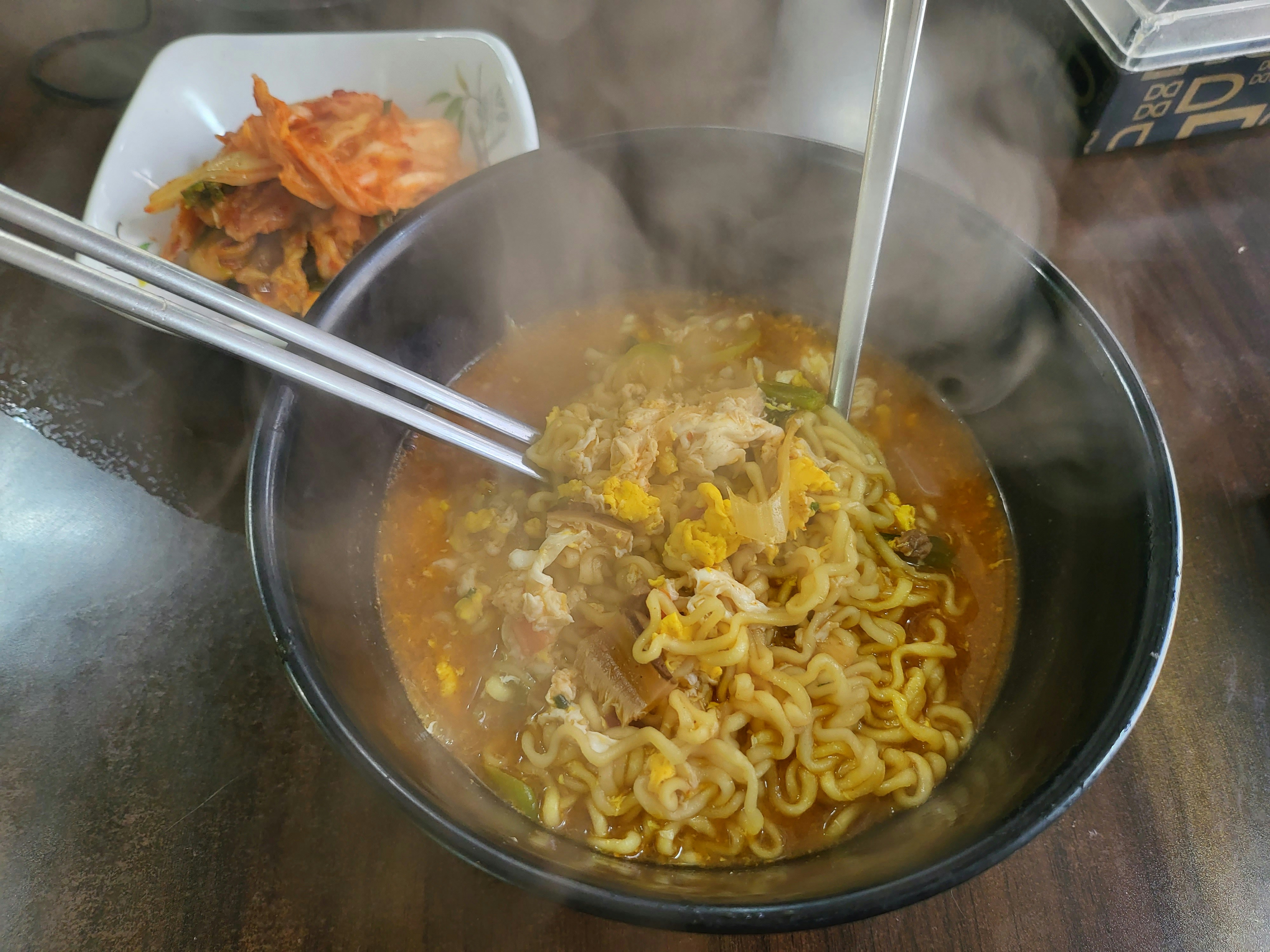 Steaming Korean ramen noodle soup with soft-boiled egg, spring onions, and rich savoury broth